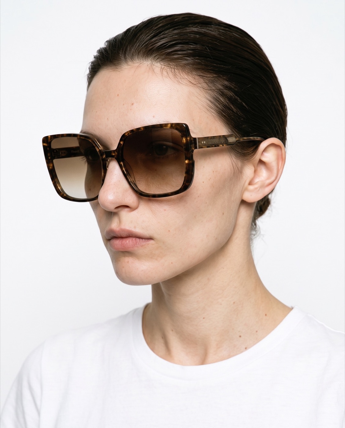 AI-generated image of the same tortoiseshell sunglasses floating over a teal gradient sky