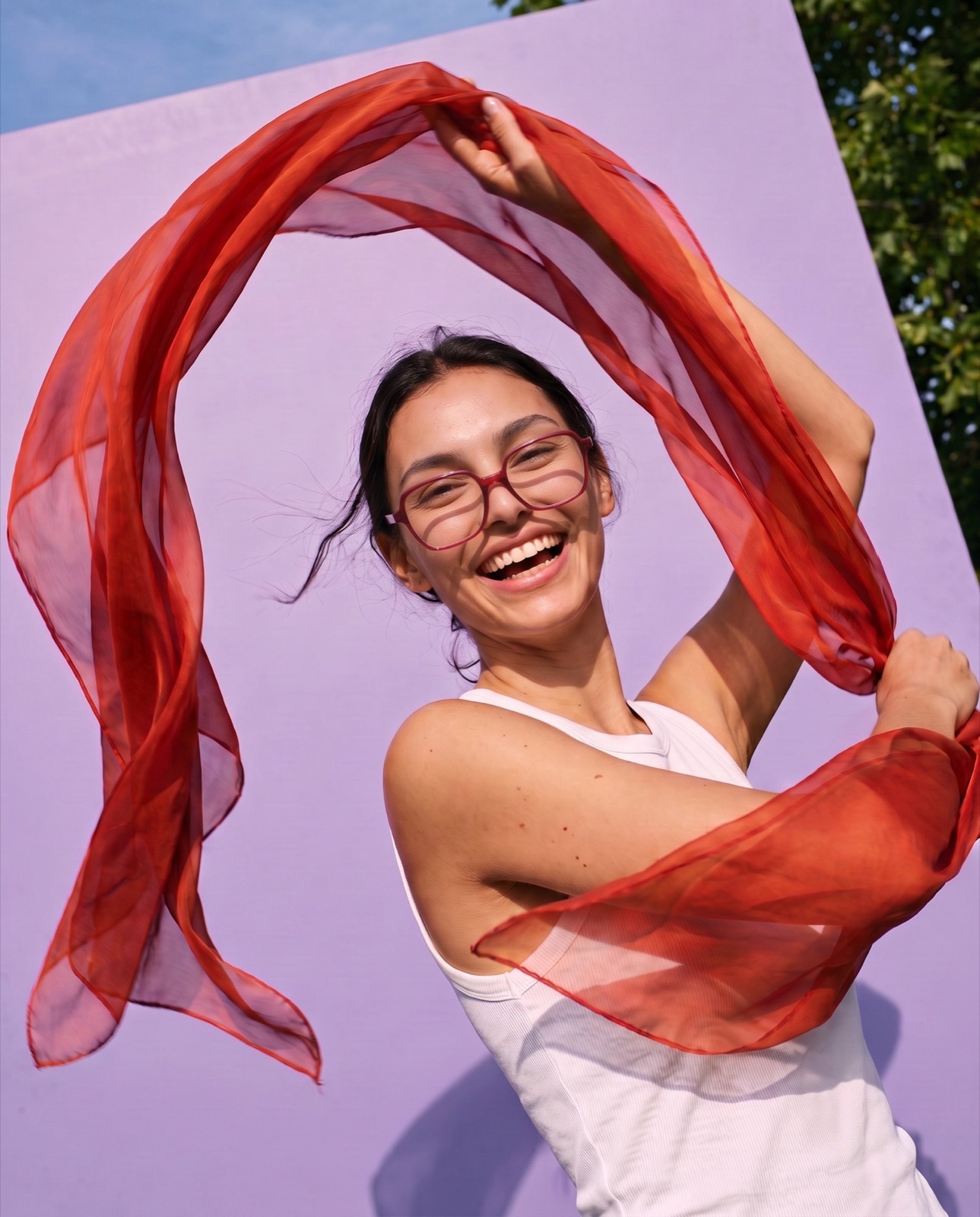 Woman laughing outdoors wearing red square glasses, colourful eyewear brand campaign