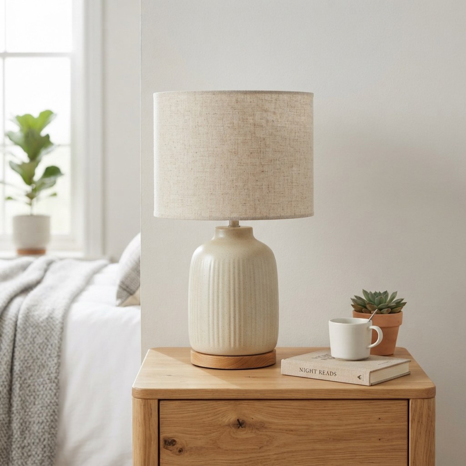 Ceramic bedside lamp on a wooden nightstand with a plant and a mug