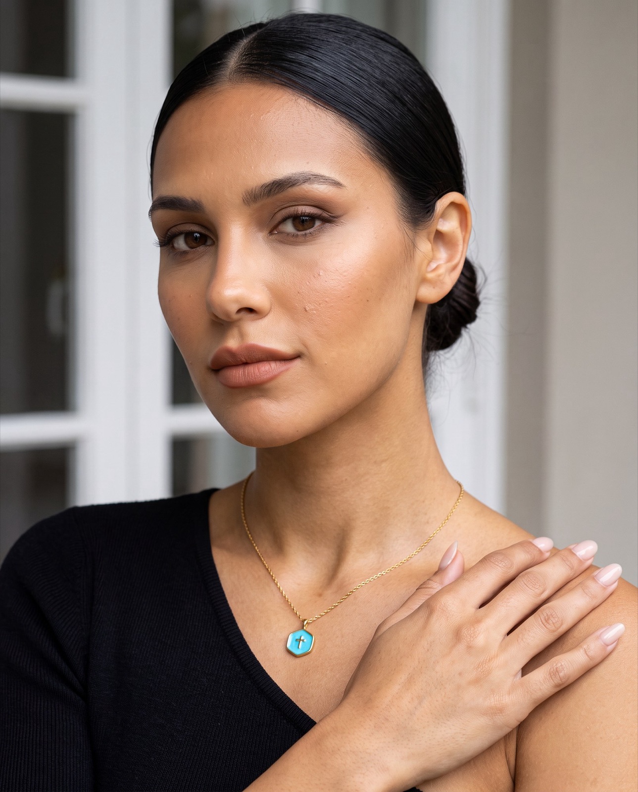 Close-up of a model wearing a gold pendant necklace and a black top