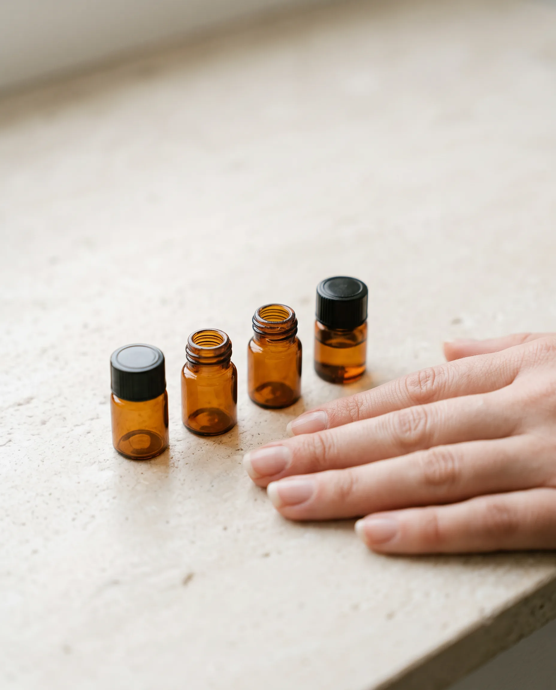 Round 2: the small squat vials beside a resting hand for true scale, matching the reference's tiny size