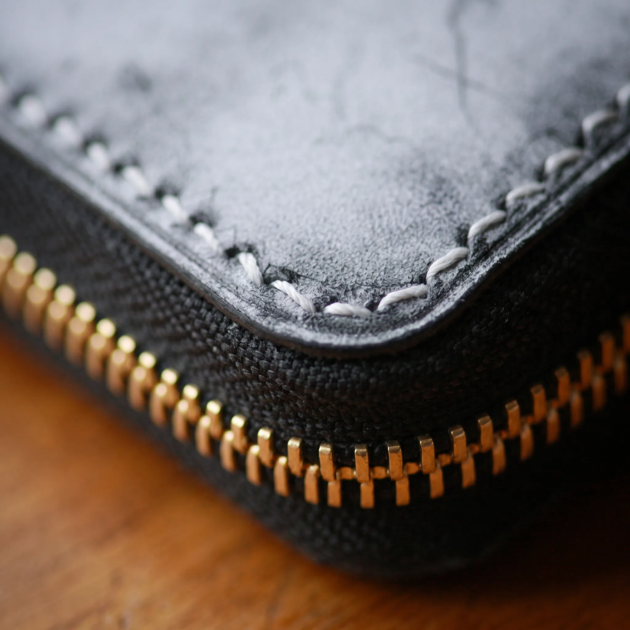 Second macro angle of the wallet's zipper pull and stitched edge